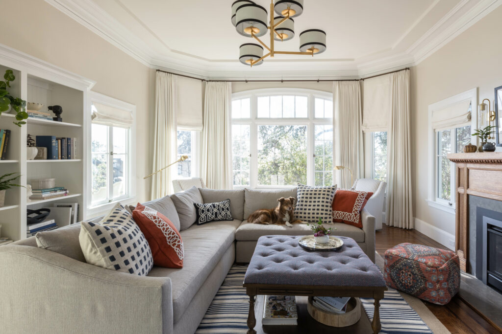 Sonoma County interior designer designs a family friendly and functional living room. Beautiful white curtains behind a performance upholstered sectional with a cute dog. A bold custom upholstered ottoman cocktail table finishes the interior design.